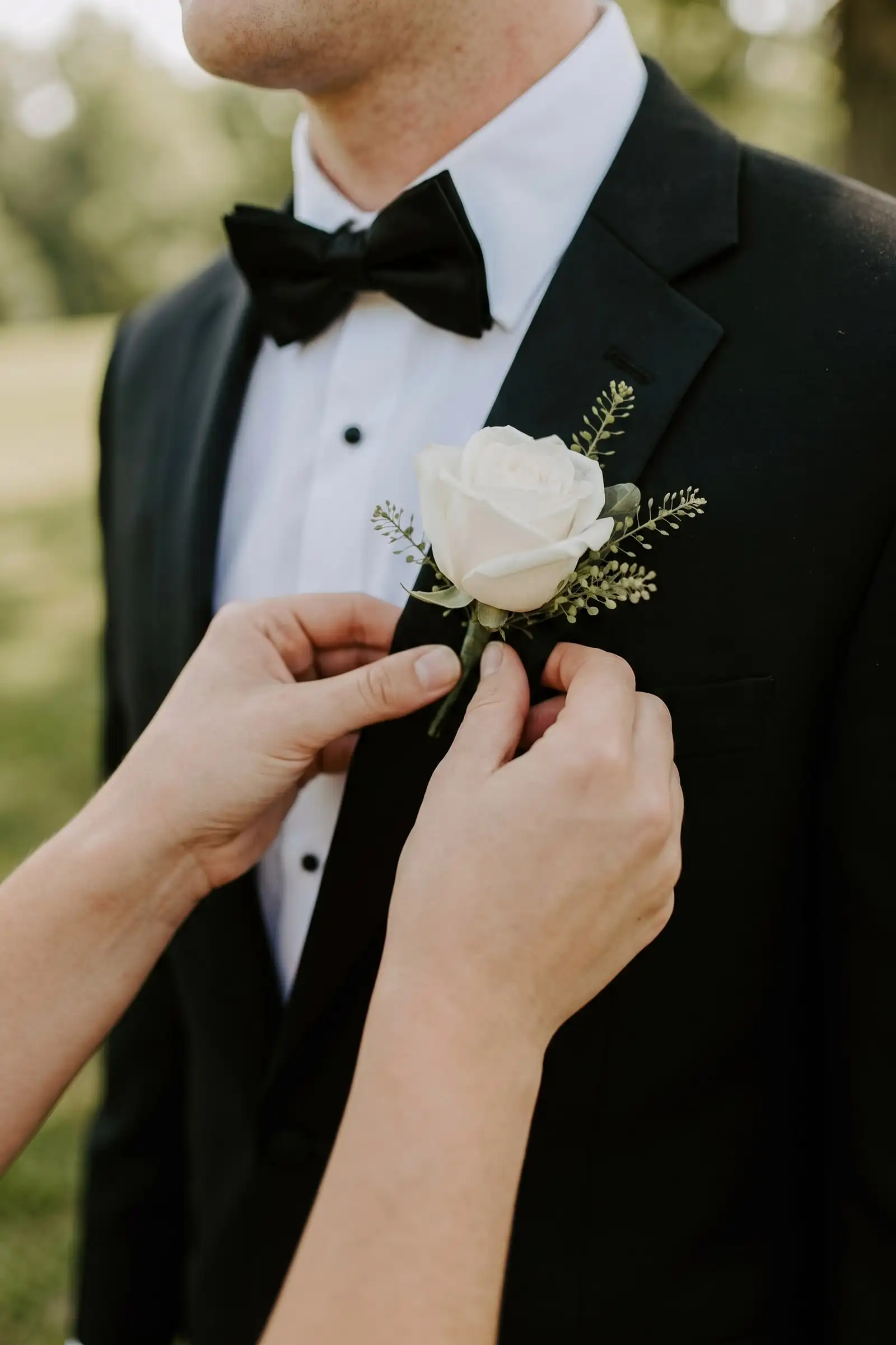A groom with a blush boutonniere pinned to his lapel