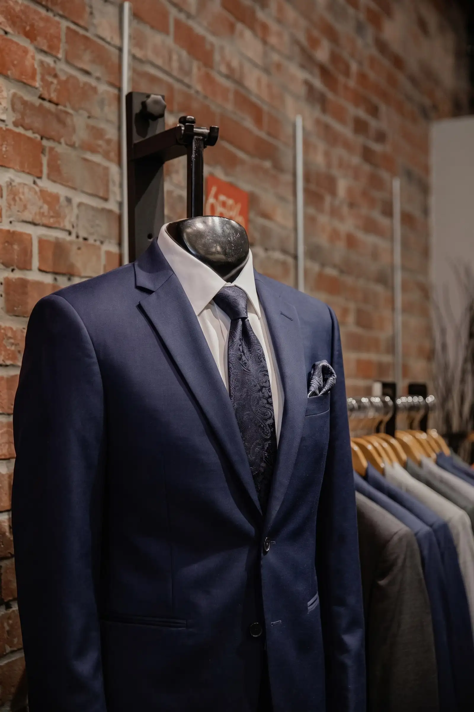 A tuxedo on display with a rack of suits at Weber's Clothing